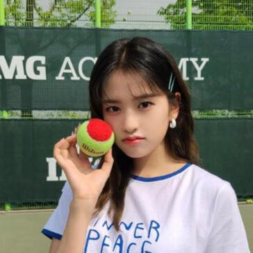 Idol Ahn Yujin holding a green and red tennis ball while making a pouty face